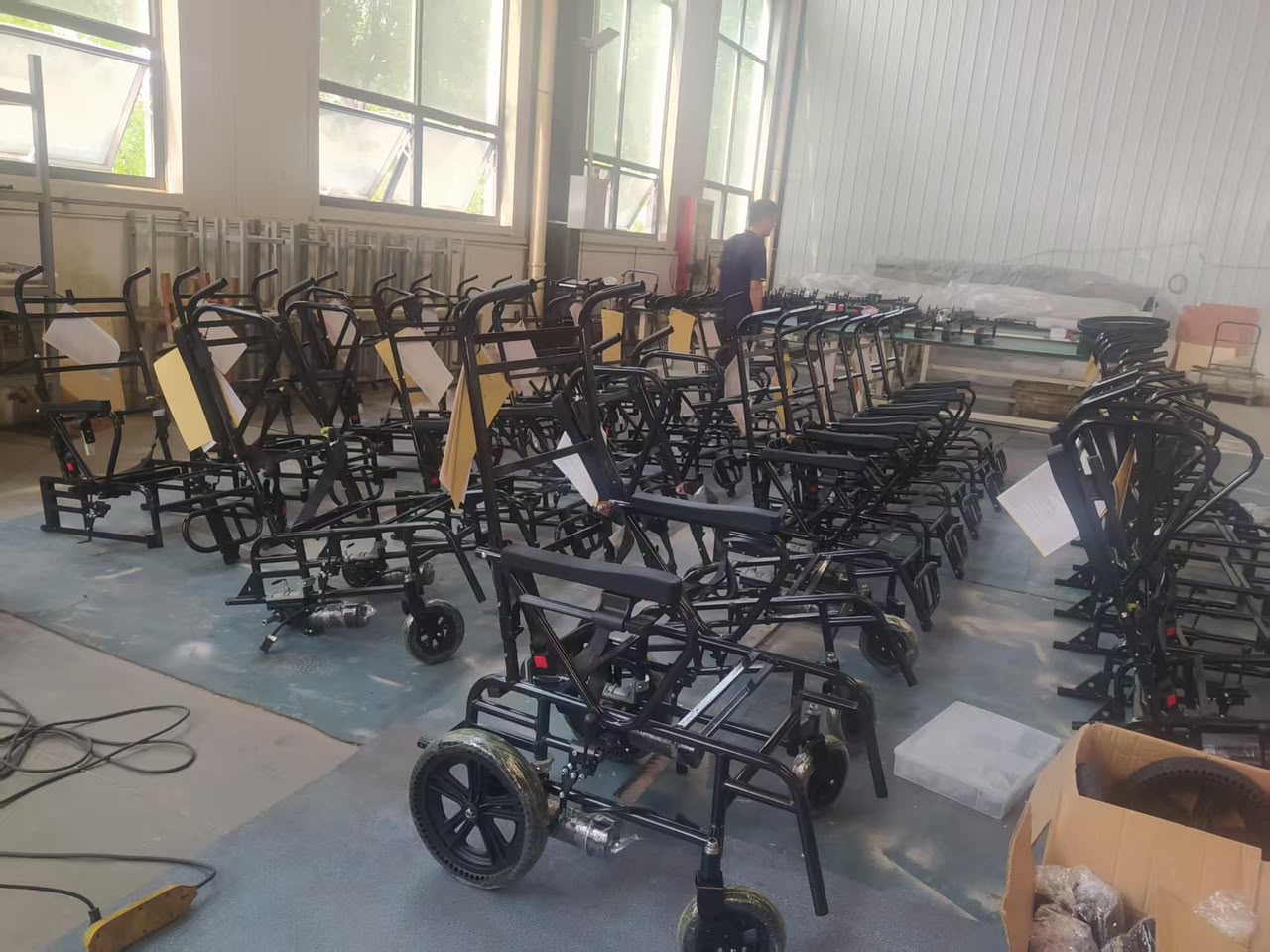 Movo X frames on the assembly line — dozens of black chassis staged in the production hall before motors, tracks and control systems are installed