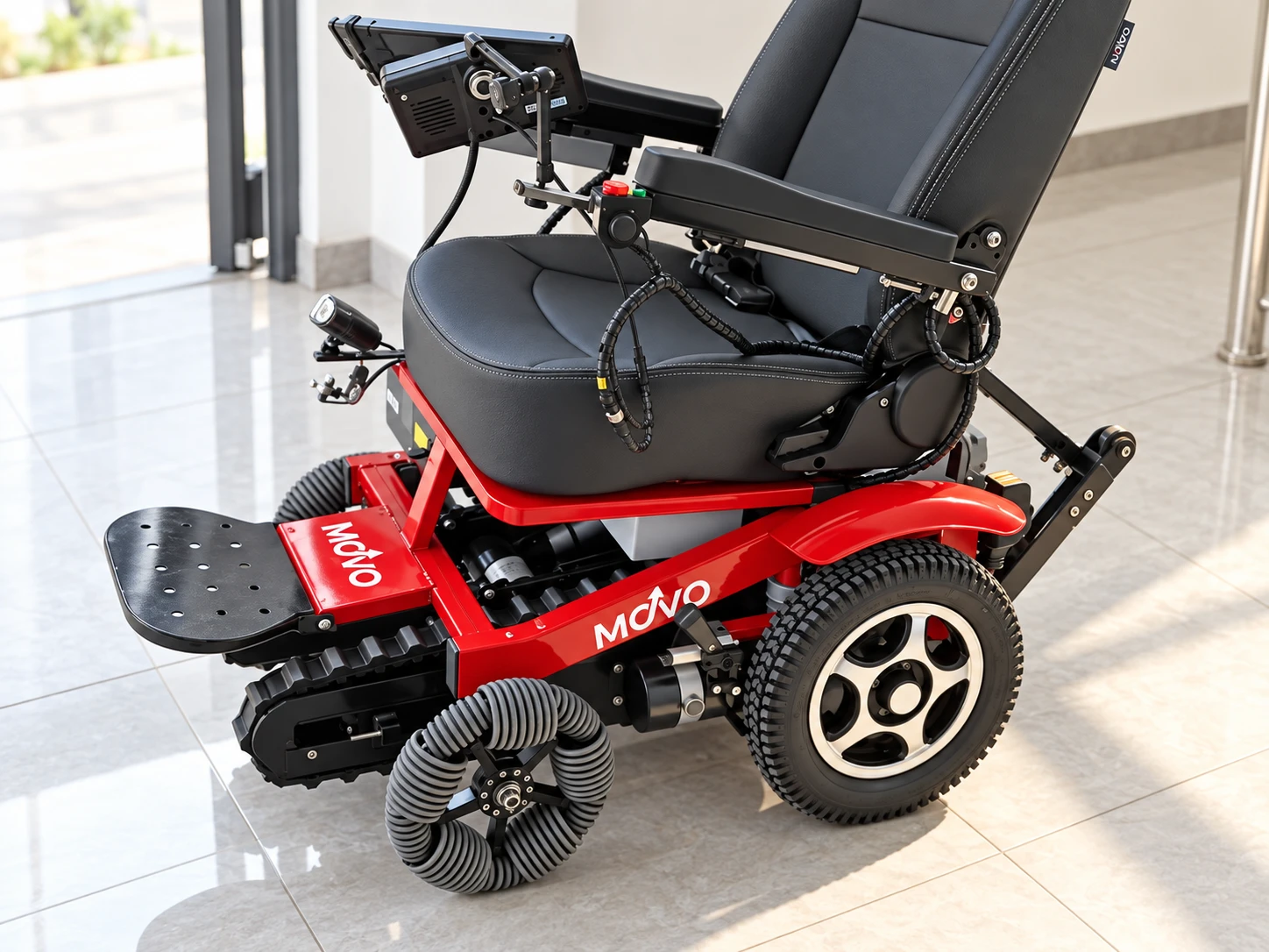 Close-up of the Movo X — red aluminum chassis with MOVO badging, black bucket seat with padded headrest, joystick controller and adjustable display arm, LED headlight, rubber stair-climbing tracks, and both wheel types the chair ships with